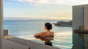 Una persona en una piscina con vista al mar y un barco a lo lejos.