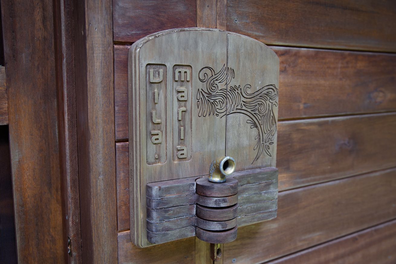 A wooden door with a metal latch and a decorative plaque with the name "Maria" engraved on it.