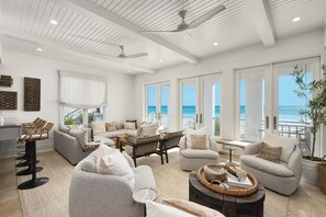 A spacious living area with multiple seating options, large windows offering ocean views, and ceiling fans. - Shared Moments | Private Beach Access | Gulf Front | Hot Tub (Panama City Beach)