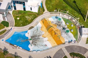 An aerial view of a water park with a pool, slides, and a fenced area.