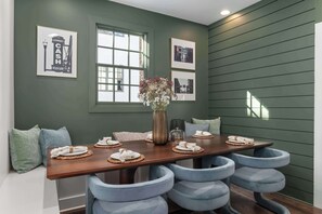 A dining area with a long table, blue cushioned chairs, a vase with flowers, and framed pictures on the wall. - The Ridgeline - New Rooftop Retreat Near The Gulch (Nashville)