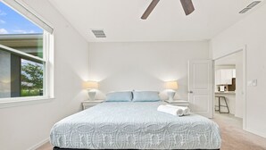Ein Schlafzimmer mit einem großen Bett, zwei Nachttischlampen, einem Fenster und einer Tür zu einem Badezimmer.
