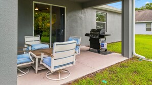 Eine überdachte Terrasse mit Gartenmöbeln und einem Grill.
