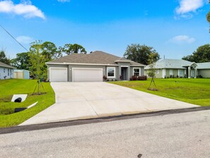 A residential house with a driveway, garage, and lawn.