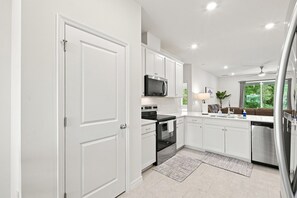 A modern kitchen with white cabinetry, a black stove, a microwave, and a dishwasher.
