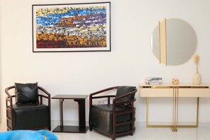 A modern room with two leather chairs, a small table, a round mirror, and a framed abstract painting on the wall. - 3bedroom Luxury Flat (Ikeja)