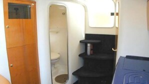 Et lille badeværelse med et træskab, toilet og en hylde.