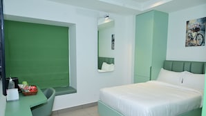 A room with a bed, a desk, a chair, a mirror, and a wall-mounted artwork. - Lumis Hotel (Bengaluru)