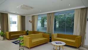 A modern living room with two yellow sofas, a small white table, and a potted plant. - Lumis Hotel (Bengaluru)