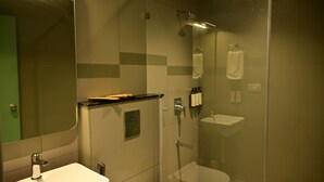 A modern bathroom with a glass-enclosed shower, a sink, and a mirror. - Lumis Hotel (Bengaluru)