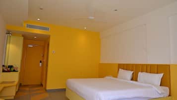 A hotel room with a bed, a desk, a mirror, and a door.
