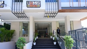 A hotel entrance with a sign reading "LUMIS HOTEL," a staircase with potted plants, and a metal railing. - Lumis Hotel (Bengaluru)