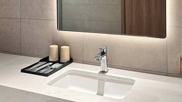 A modern bathroom with a large mirror, a sink with a faucet, and a wooden cabinet.