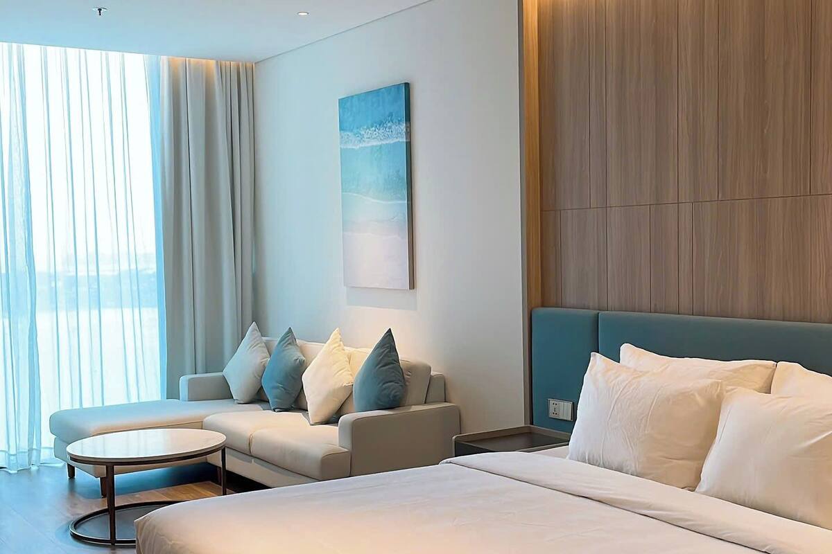 Une chambre à coucher moderne avec un grand lit, un canapé, une table basse et un tableau au mur.