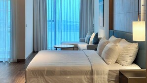 A modern hotel room with a large bed, a seating area, and a view of the outdoors. - A La carte Ha Long Apartment Sea View  (Bai Chay)