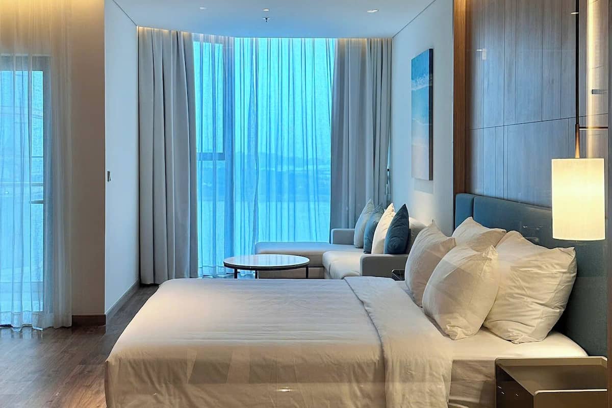 Une chambre d’hôtel moderne dotée d’un grand lit, d’un coin salon et offrant une vue sur l’extérieur.
