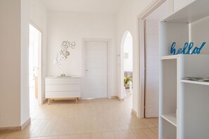 Un pasillo con una puerta blanca, un aparador blanco y un cartel con la palabra 'hello' sobre una estantería.