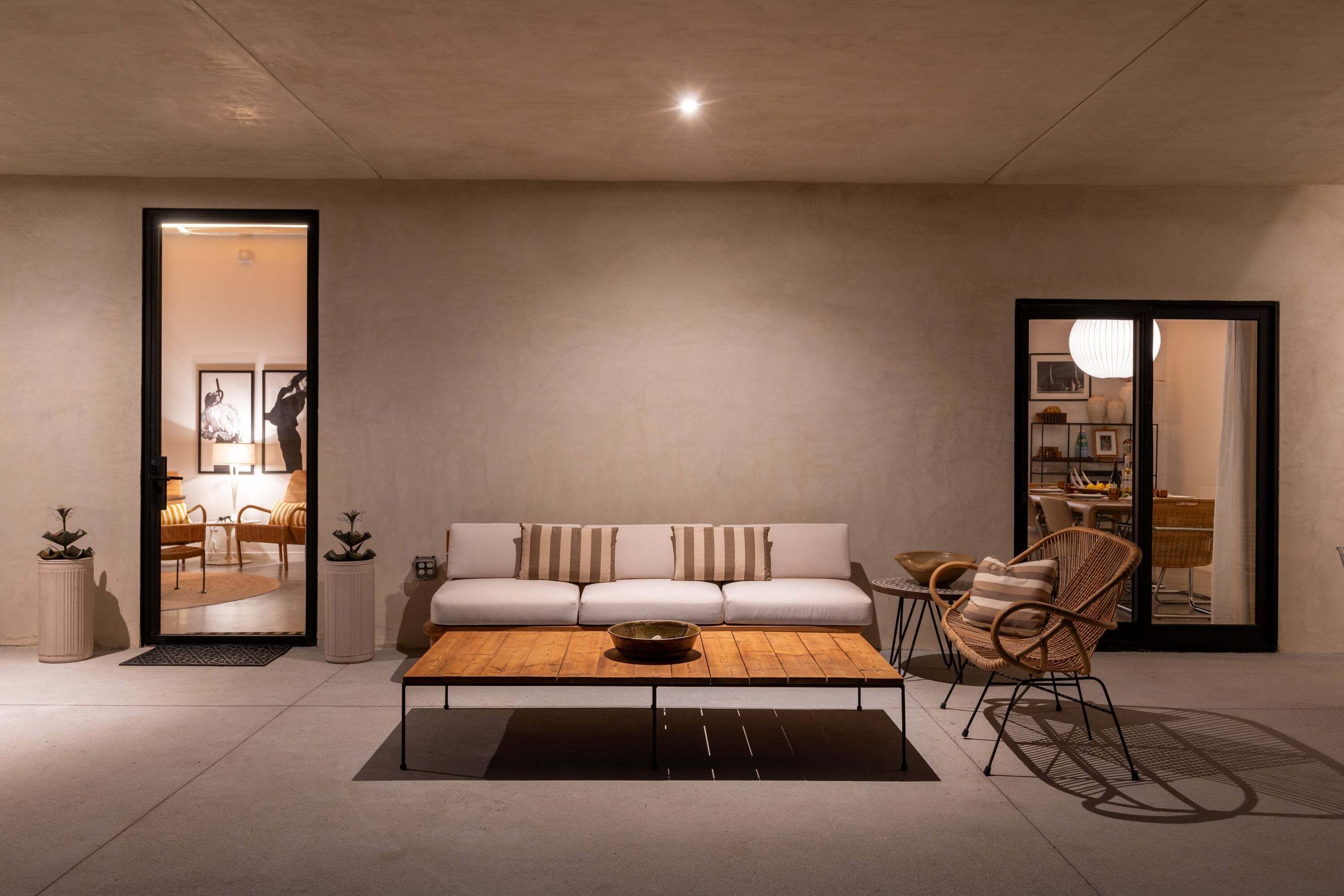 Un salon moderne avec un canapé, une table basse et des fauteuils en osier.