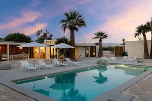 A pool area with lounge chairs and umbrellas, surrounded by palm trees and modern architecture. - The Villa - Modern Meditative PS Retreat (Palm Springs)
