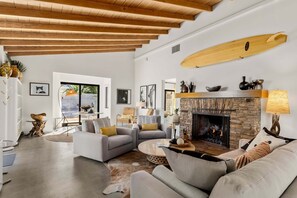 A spacious living area with a fireplace, modern furniture, and a wooden ceiling. - The Villa - Modern Meditative PS Retreat (Palm Springs)
