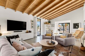 A modern living room with a flat-screen TV, sofas, a coffee table, and a bookshelf. - The Villa - Modern Meditative PS Retreat (Palm Springs)