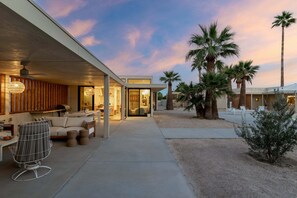 A modern house with a covered patio, outdoor seating, and palm trees. - The Villa - Modern Meditative PS Retreat (Palm Springs)
