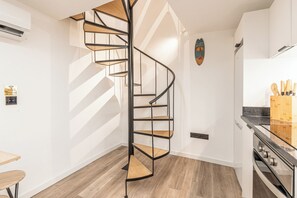 A modern kitchen with a spiral staircase, wooden flooring, and a built-in oven. - Yellow Wave (Paúl do Mar)