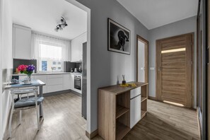 Eine moderne Küche mit weißen Schränken, ein Essbereich mit Tisch und Stühlen sowie ein Holztisch.