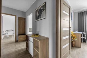 Ein modernes Zimmer mit Schreibtisch aus Holz, Essbereich und großem Fenster.