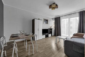 Ein modernes Wohnzimmer mit Essbereich, Flachbildfernseher und einer Couch.