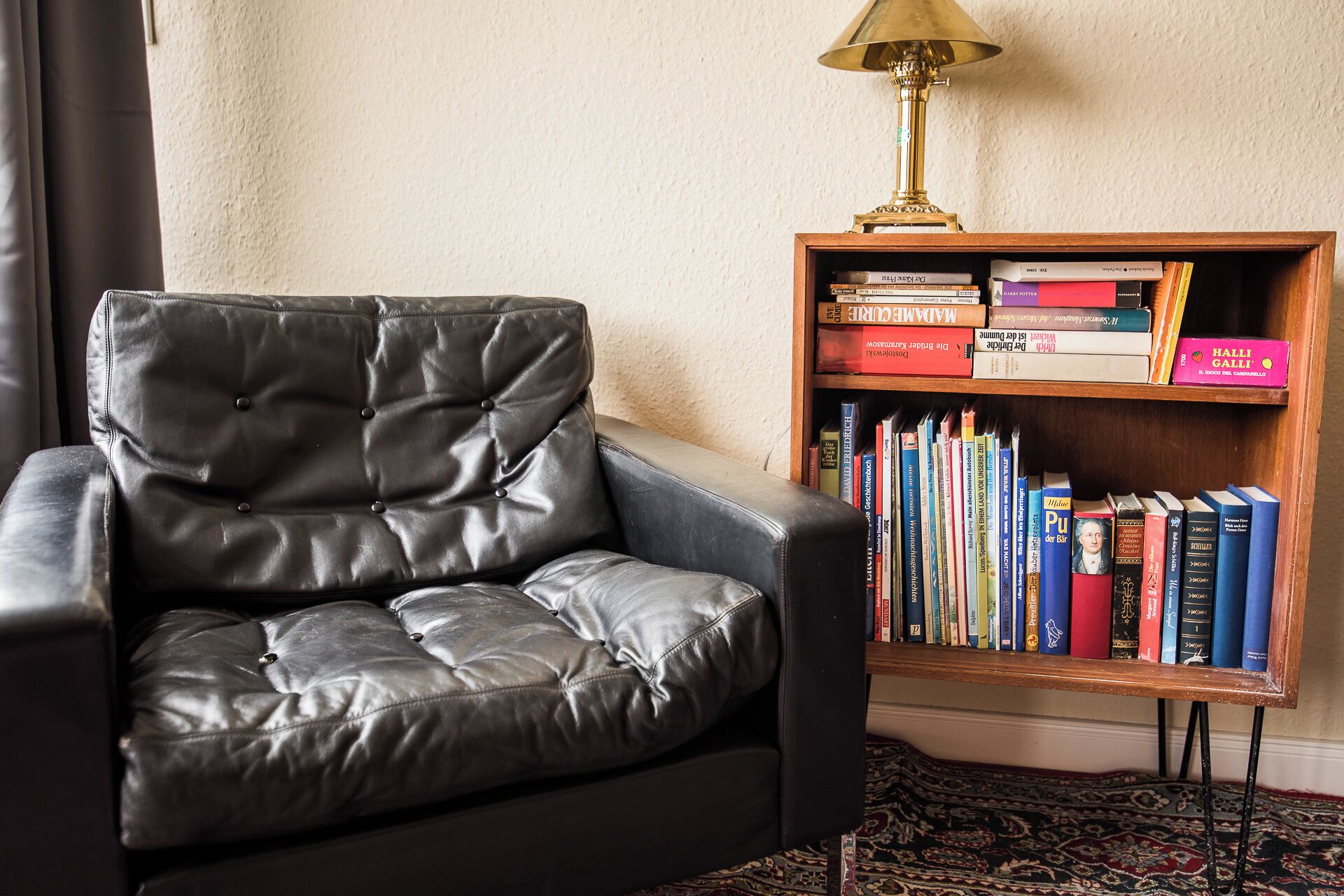 Un fauteuil en cuir et une bibliothèque remplie de divers ouvrages.