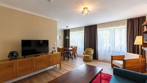 Een moderne woonkamer met een flatscreen televisie, houten meubels, een eettafel en een bank.