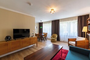Een moderne woonkamer met een flatscreen televisie, houten meubels, een eettafel en een bank.