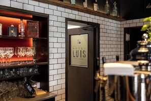 Een hotelbar met een bord waarop 'HOTEL LUIS' staat, en diverse flessen en glazen op planken.