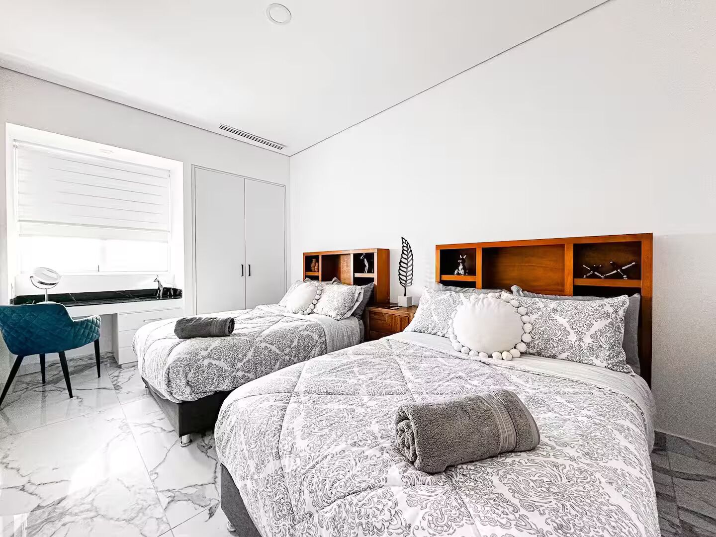 A bedroom with two beds, a desk, and a chair.