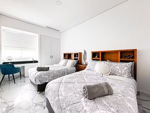 Ein Schlafzimmer mit zwei Betten, einem Schreibtisch und einem Stuhl.