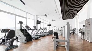 A modern gym with treadmills, weight machines, and large windows. - Charming apartment, incredible view (Zapopan)