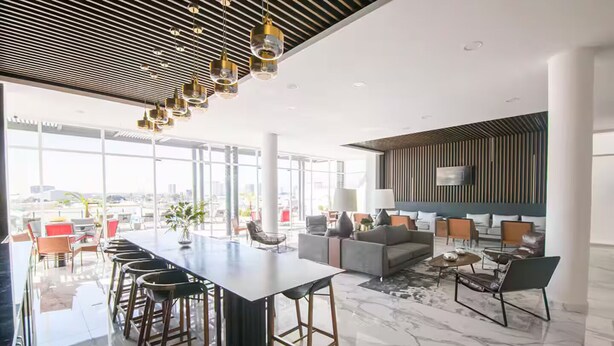 Een modern interieur met een lange bar, een zithoek en grote ramen met uitzicht over de stad.