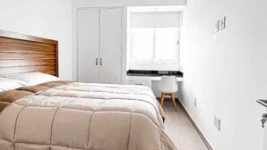 Een slaapkamer met een bed, een bureau en een kledingkast.
