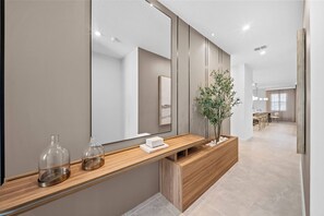 Enter a stylish hallway with a sleek wooden console, elegant decor, and a potted plant, creating a warm welcome. The soft lighting and neutral tones set a calm atmosphere, inviting you to discover more of the home. - 6BR house with game room near Disney (Kissimmee)