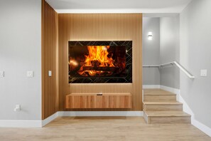 Ein modernes Interieur mit einer Holzwand, einem Kamin mit Feuer und einer Treppe.