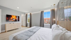 Quarto moderno com uma cama grande, televisão de tela plana, cômoda e vista para um edifício.