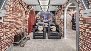 A room with brick walls, leather recliners, a luggage cart, and a mural of a cityscape. - 7BR house sleeps 20 with hot tub and pool (Kissimmee)
