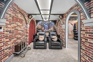 A room with brick walls, leather recliners, a luggage cart, and a mural of a cityscape. - 7BR house sleeps 20 with hot tub and pool (Kissimmee)