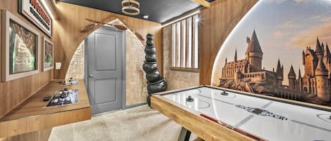 A room with a pool table, a mural of a castle, and a wooden ceiling.