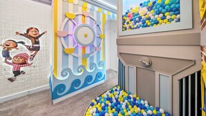 A children's play area with a ball pit, colorful wall decorations, and cartoon characters. - 7BR house sleeps 20 with hot tub and pool (Kissimmee)