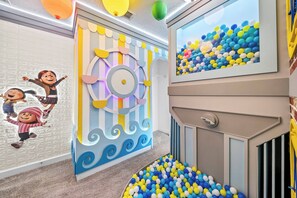 A children's play area with a ball pit, colorful wall decorations, and cartoon characters. - 7BR house sleeps 20 with hot tub and pool (Kissimmee)