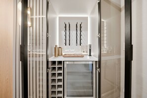 A modern kitchen with a built-in wine rack, a countertop with glassware, and a wine bottle. - 7BR house at Windsor Cay Resort near Disney (Clermont)