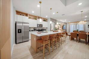 A modern kitchen with a central island, stainless steel appliances, and wooden accents. - 7BR house at Windsor Cay Resort near Disney (Clermont)