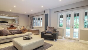 A spacious living room with a sofa set, a leather armchair, and a coffee table. - Woodlands House (Ringwood)